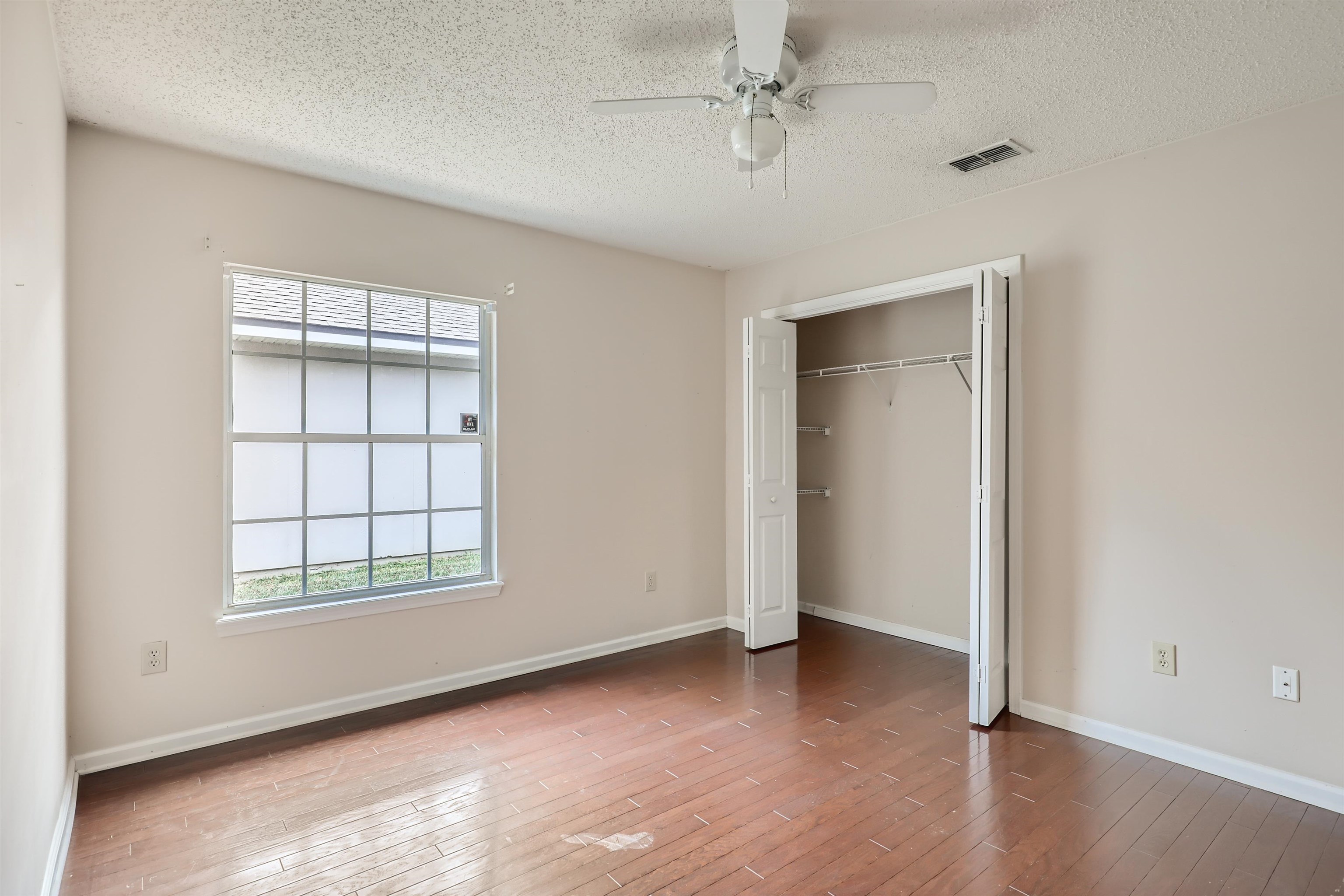 3684 Eagle Ridge Drive Jacksonville, FL 32224 - Photo 24 of 33 an empty room with wooden floor ceiling fan and windows