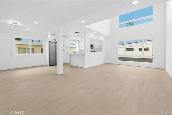 a view of empty room with windows and refrigerator