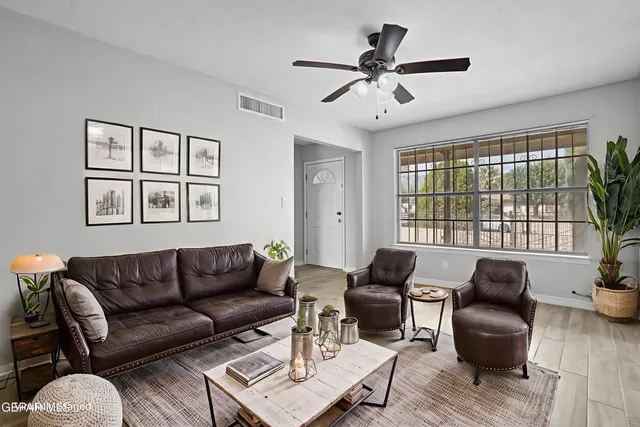 a living room with furniture a ceiling fan a fireplace and a large window