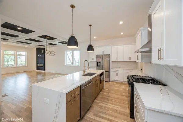 a kitchen with stainless steel appliances granite countertop a sink a stove and a wooden floors