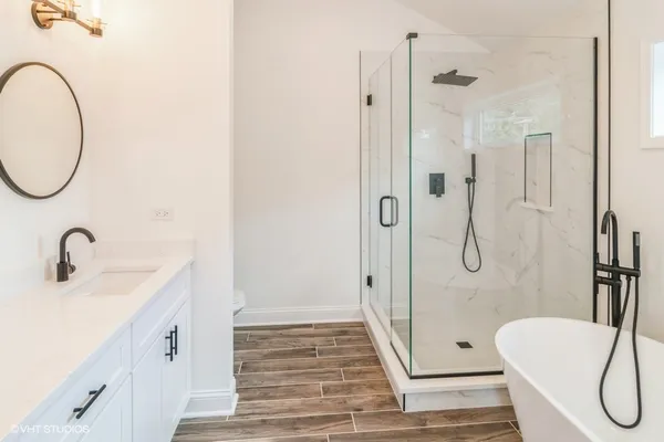 a bathroom with a sink a toilet a mirror and shower