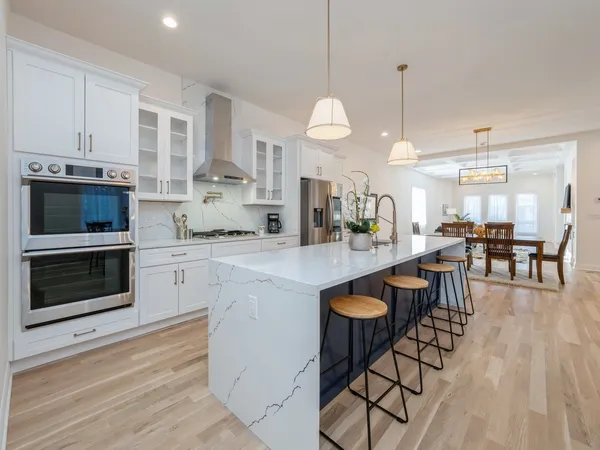 a kitchen with stainless steel appliances granite countertop a stove a sink and a wooden floor