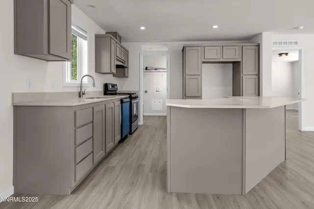 a kitchen with stainless steel appliances a sink cabinets and wooden floor