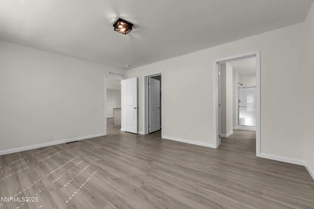 a view of an empty room with wooden floor and closet