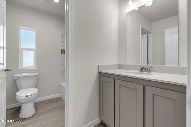 a bathroom with a granite countertop sink a toilet and a mirror