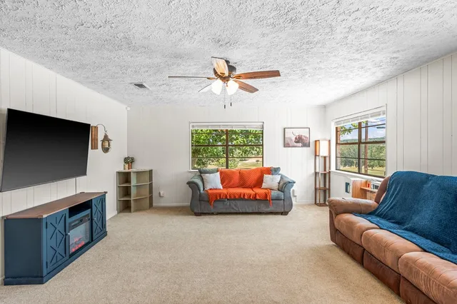 a living room with furniture a flat screen tv and a large window