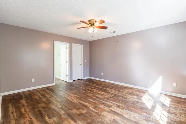 a view of an empty room with window and chandelier fan