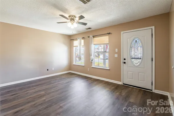an empty room with wooden floor fan and windows