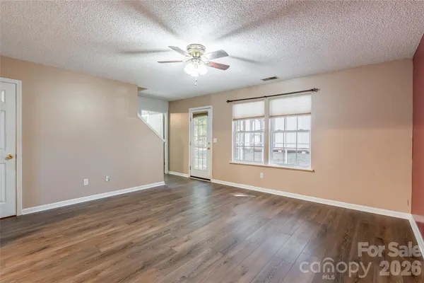 a view of an empty room with wooden floor and a window