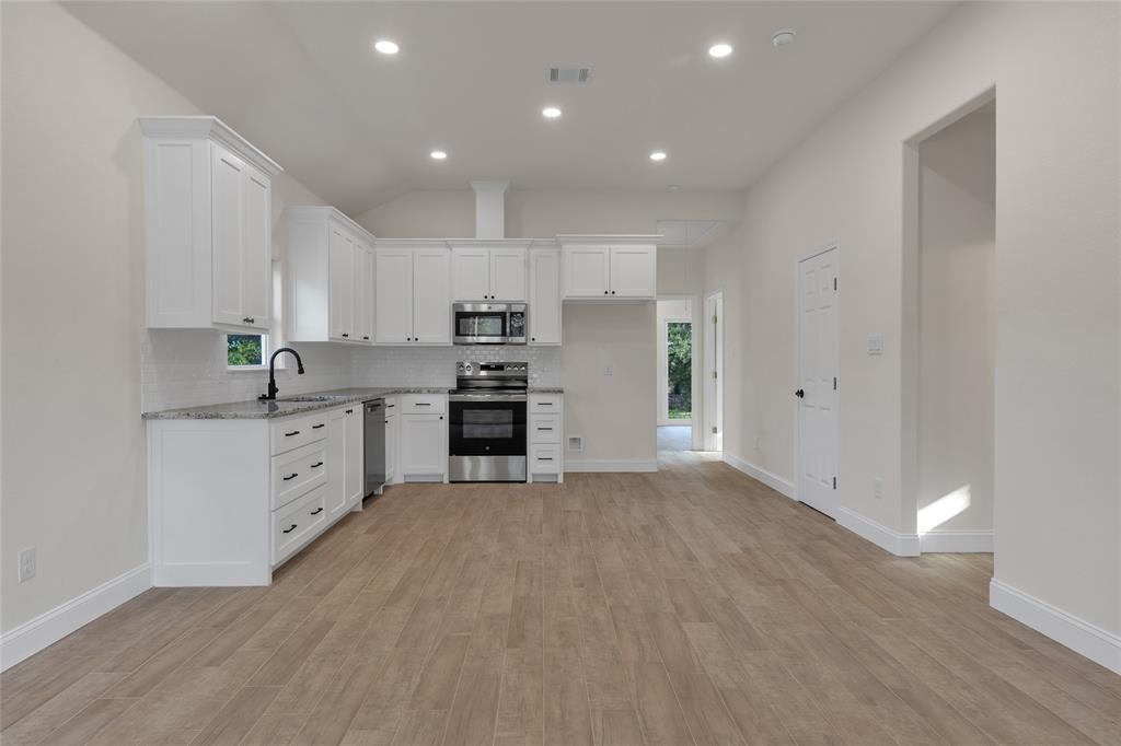 815 Southwest 28th Street Mineral Wells, TX 76067 - Photo 14 of 40 a large white kitchen with white cabinets stainless steel appliances and a window