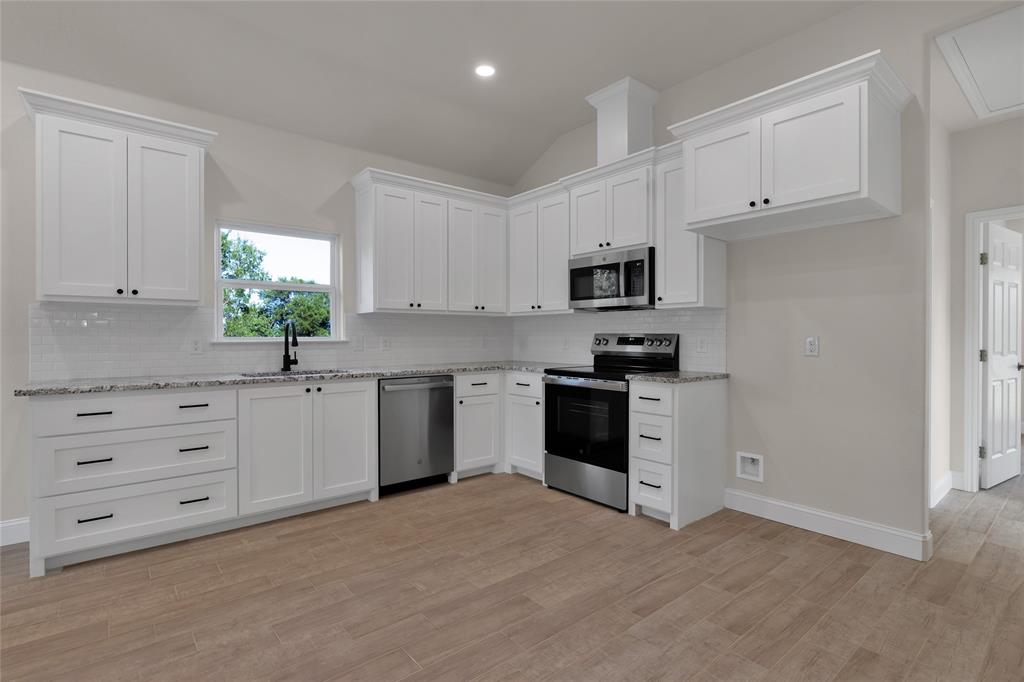 815 Southwest 28th Street Mineral Wells, TX 76067 - Photo 15 of 40 a kitchen with white cabinets stainless steel appliances and window