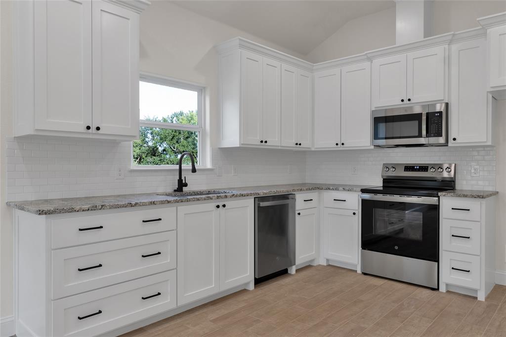 815 Southwest 28th Street Mineral Wells, TX 76067 - Photo 17 of 40 a kitchen with granite countertop white cabinets appliances and a window