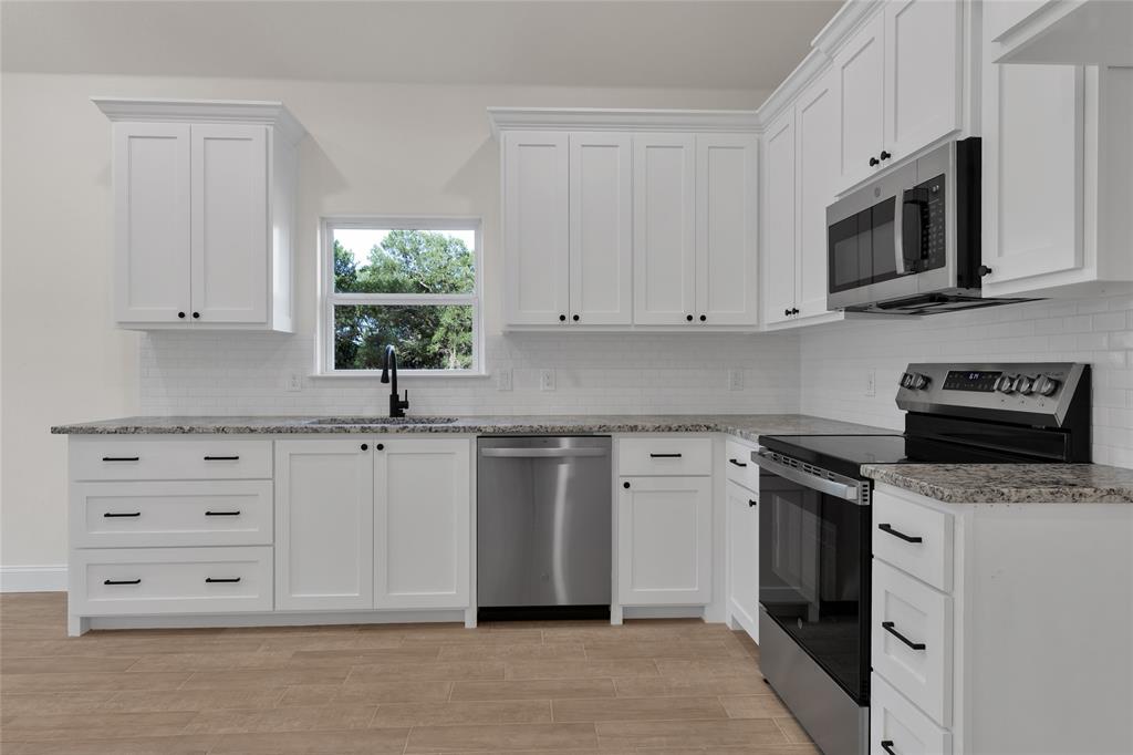 815 Southwest 28th Street Mineral Wells, TX 76067 - Photo 18 of 40 a kitchen with cabinets appliances a sink and a window