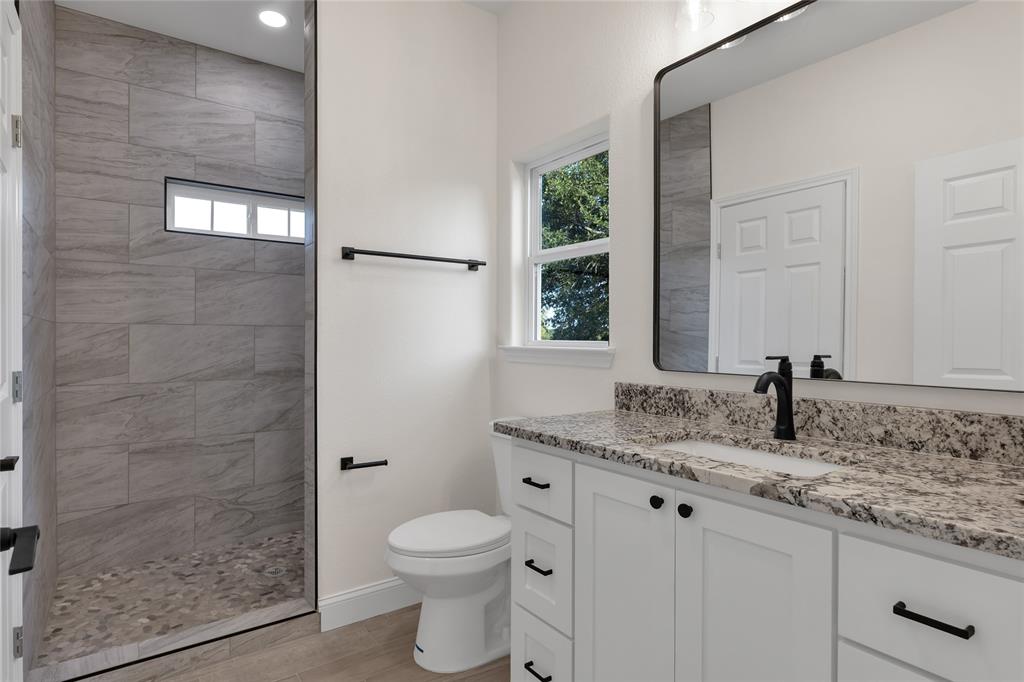 815 Southwest 28th Street Mineral Wells, TX 76067 - Photo 27 of 40 a bathroom with a granite countertop sink a toilet and shower