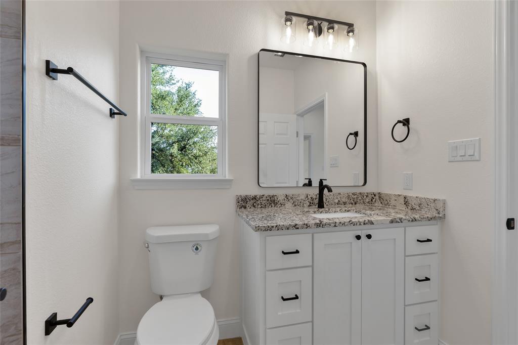 815 Southwest 28th Street Mineral Wells, TX 76067 - Photo 29 of 40 a bathroom with a granite countertop toilet a sink and a mirror