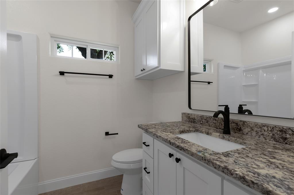815 Southwest 28th Street Mineral Wells, TX 76067 - Photo 32 of 40 a bathroom with a granite countertop sink and a mirror
