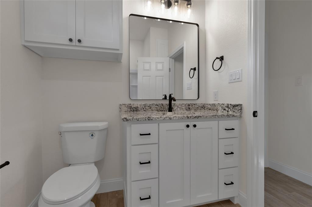 815 Southwest 28th Street Mineral Wells, TX 76067 - Photo 33 of 40 a bathroom with a granite countertop toilet sink and mirror