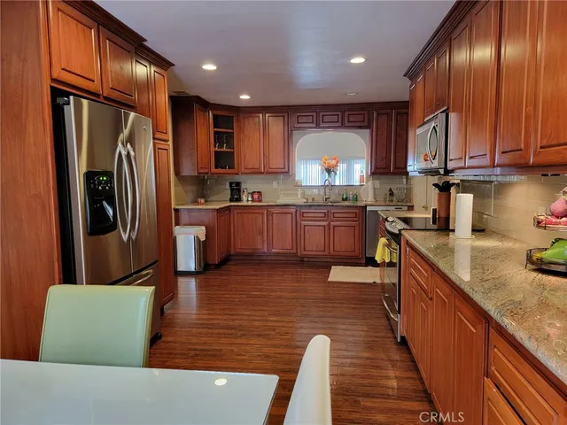 a large kitchen with stainless steel appliances granite countertop a refrigerator a stove top oven and a sink