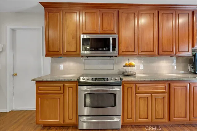 a kitchen with granite countertop wood cabinets and a stove top oven