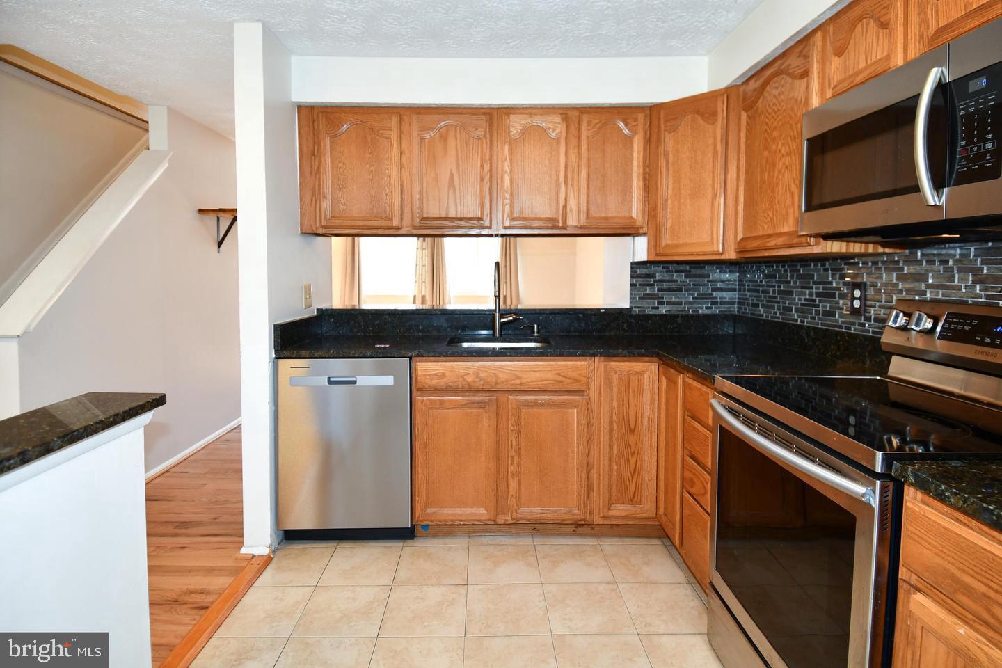 8417 Cedar Falls Court Springfield, VA 22153 - Photo 11 of 34 a kitchen with granite countertop a stove a sink and a microwave