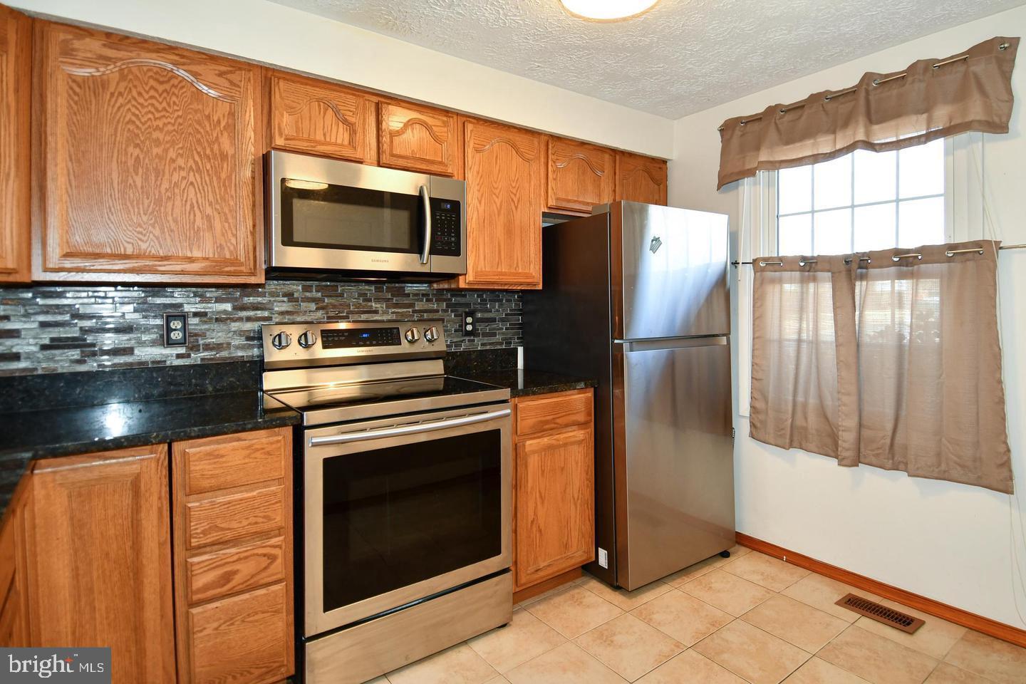 8417 Cedar Falls Court Springfield, VA 22153 - Photo 12 of 34 a kitchen with stainless steel appliances granite countertop a refrigerator stove and microwave