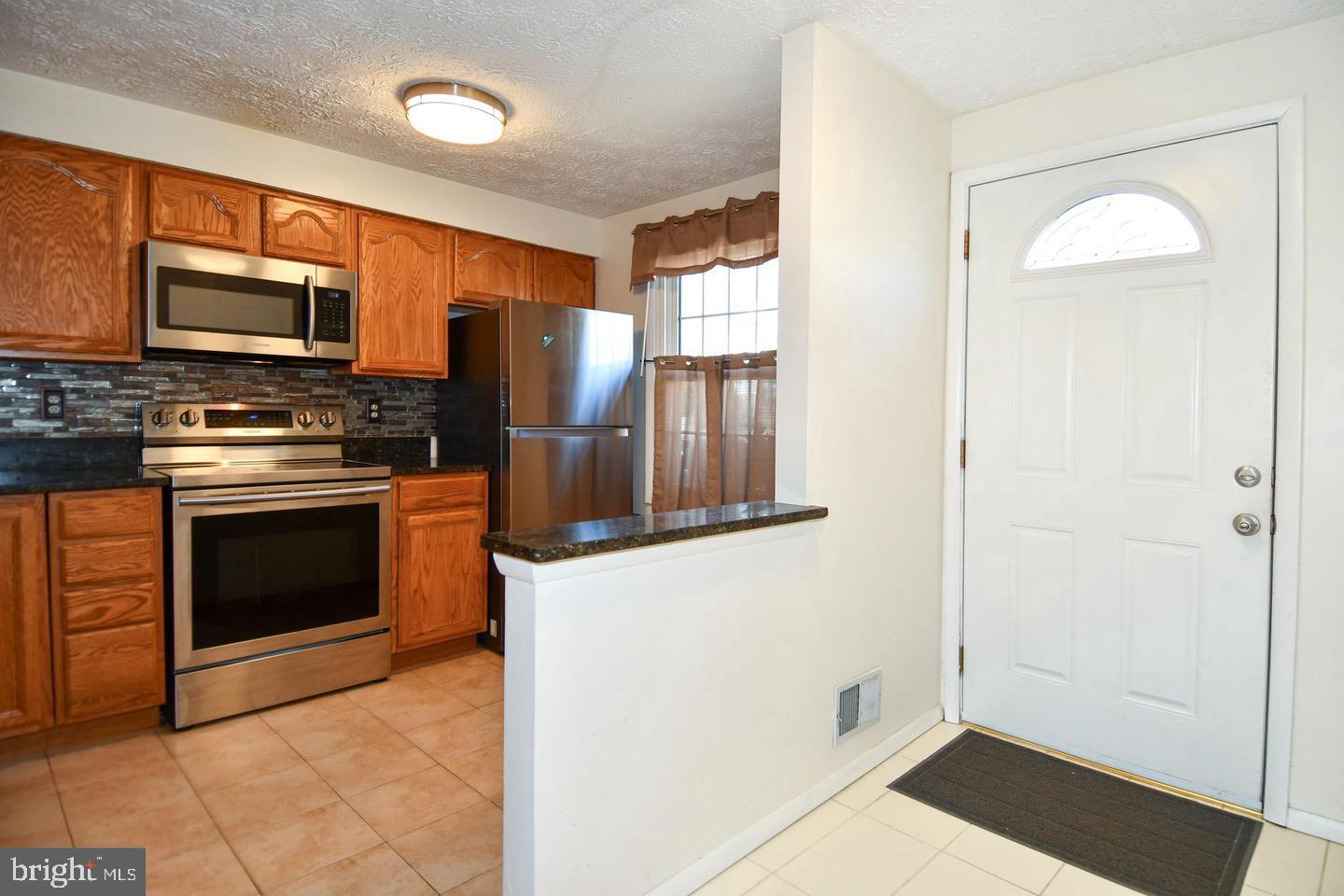 8417 Cedar Falls Court Springfield, VA 22153 - Photo 14 of 34 a kitchen with stainless steel appliances granite countertop a stove a sink and a refrigerator