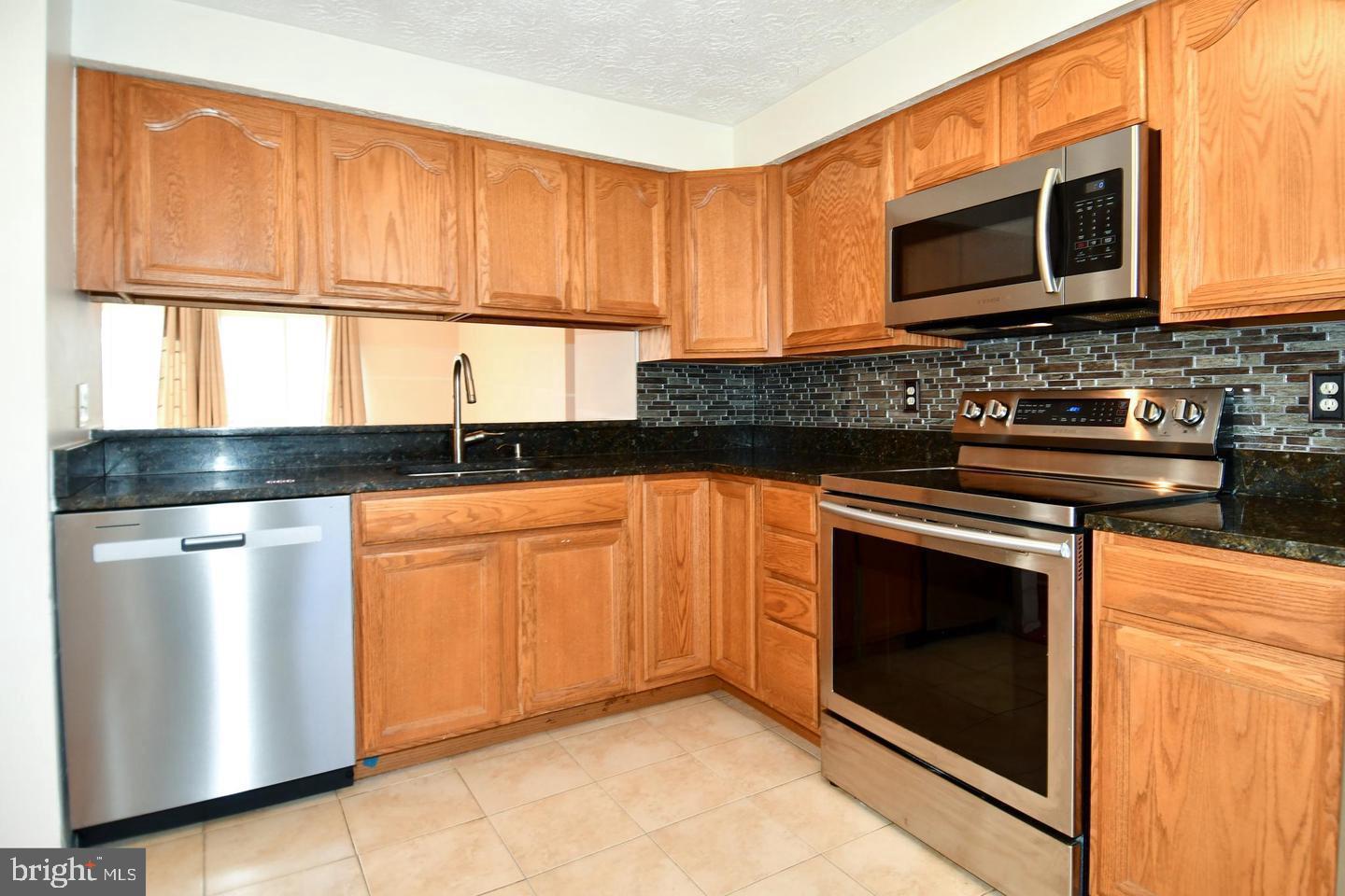 8417 Cedar Falls Court Springfield, VA 22153 - Photo 10 of 34 a kitchen with granite countertop a stove top oven cabinetry a sink and a microwave