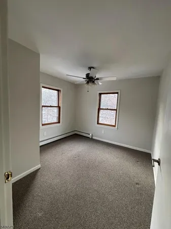 an empty room with windows and ceiling fan
