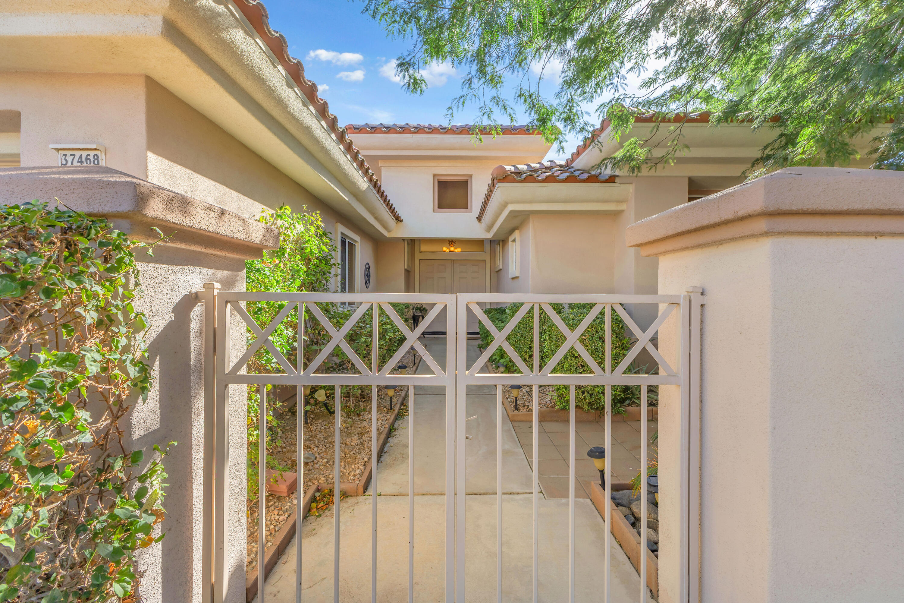 37468 Westridge Avenue Palm Desert, CA 92211 - Photo 4 of 40 a view of a brick house with a large window and wooden fence
