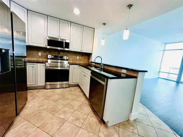 a kitchen with stainless steel appliances granite countertop white cabinets and a stove a microwave
