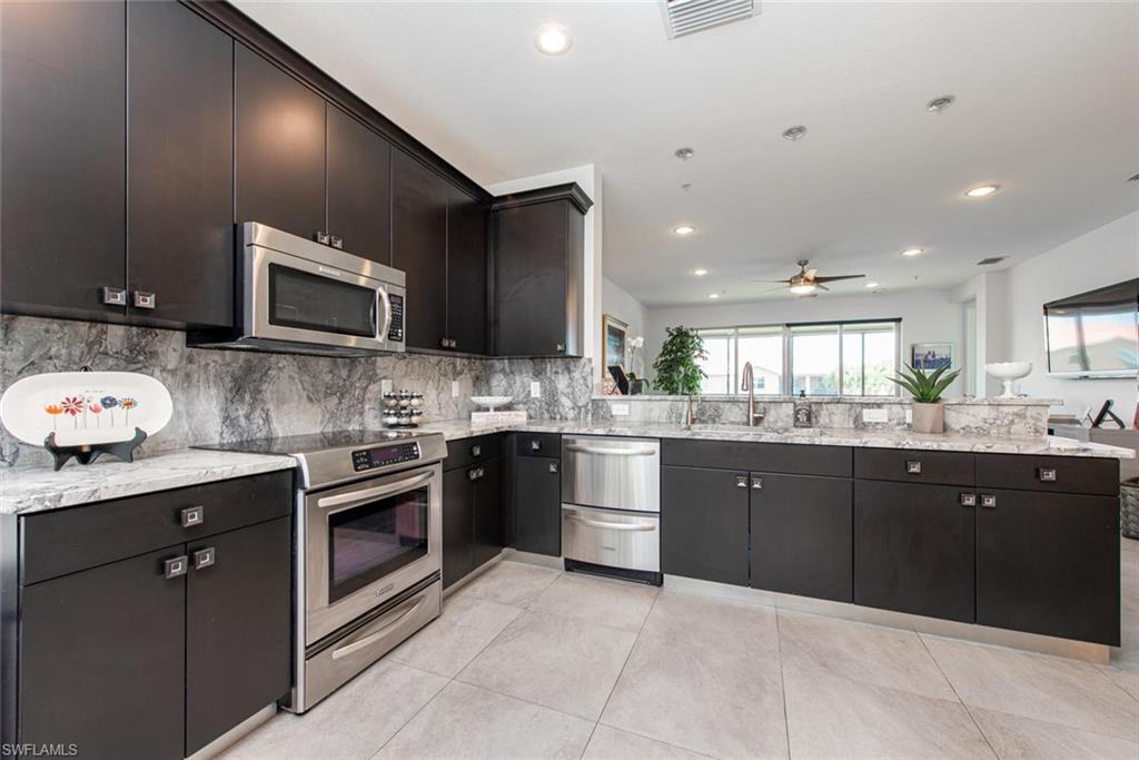 6521 Monterey Point, Unit 203 Naples, FL 34105 - Photo 3 of 17 a large kitchen with stainless steel appliances granite countertop a sink counter space cabinets and a large window