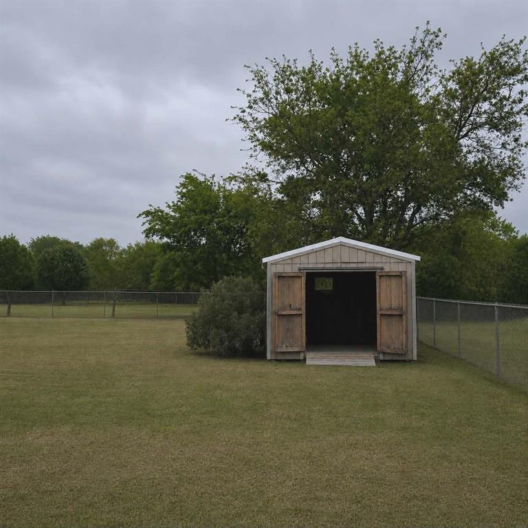 14752 Ranch Road Forney, TX 75126 - Photo 37 of 40 Detached outdoor storage shed with double wooden doors and a pitched roof