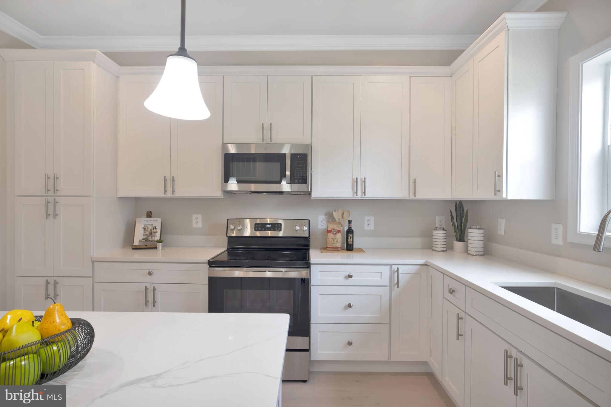 2417 Elvans Road Southeast Washington, DC 20020 - Photo 27 of 48 a kitchen with stainless steel appliances white cabinets a sink a stove a window and cabinetry