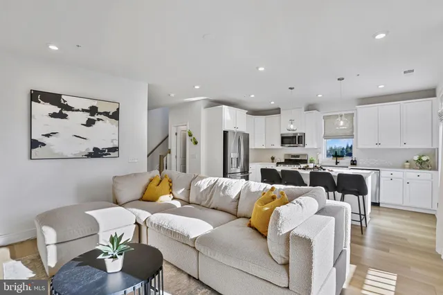a living room with furniture kitchen view and a wooden floor