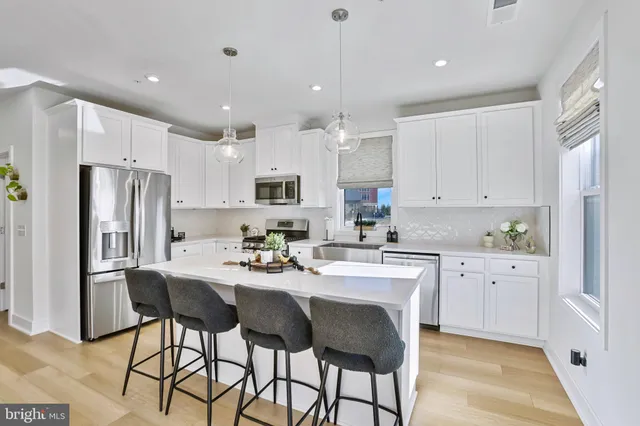 a kitchen with stainless steel appliances kitchen island granite countertop a dining table chairs refrigerator and microwave