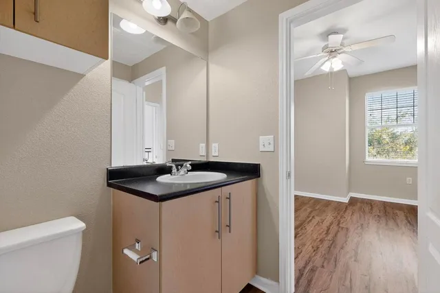 an empty room with wooden floor fan and windows