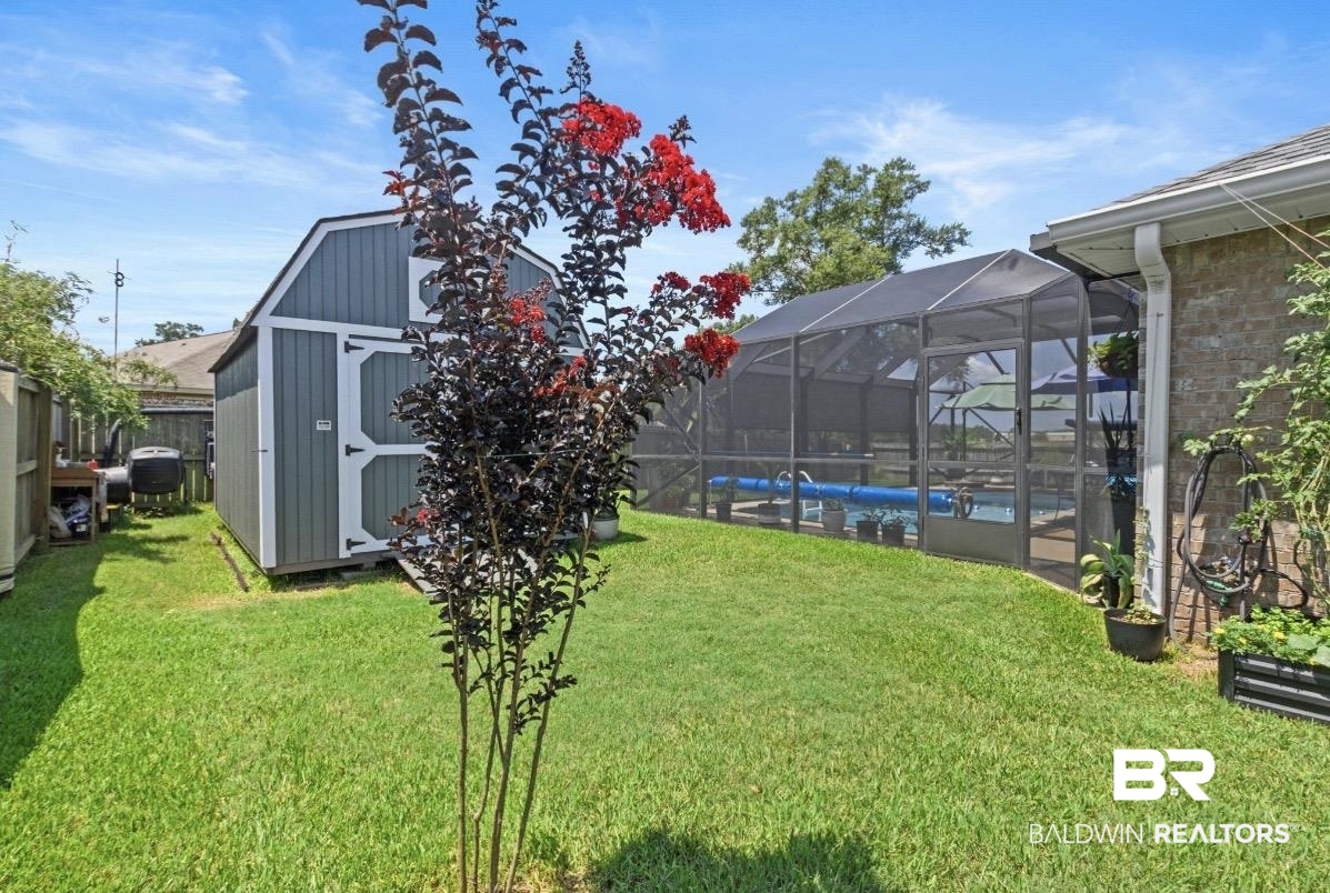1676 Abbey Loop Foley, AL 36535 - Photo 23 of 31 Expansive backyard featuring a manicured lawn, a screened-in swimming pool enclosure, and a gray storage shed with white trim