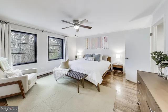 a spacious bedroom with a bed a couch and potted plant on the dresser