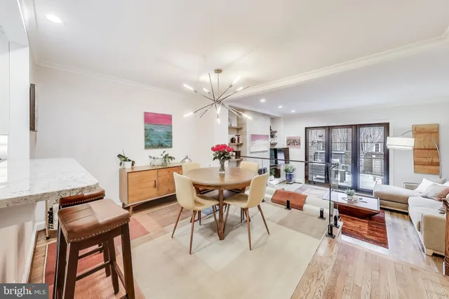 a dining room with wooden floor a chandelier fan a wooden table and chairs