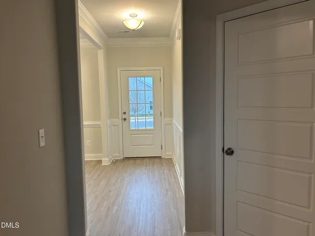 a view of a hallway with wooden floor and a bathroom