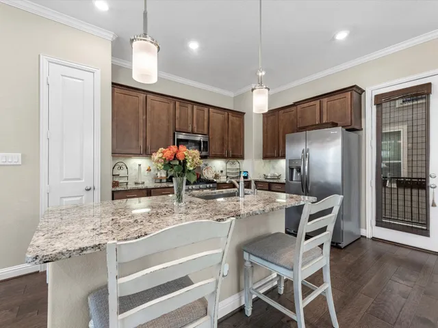 a kitchen with kitchen island granite countertop a counter space cabinets stainless steel appliances and a chandelier