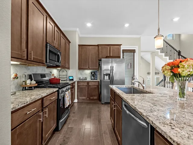 a kitchen with stainless steel appliances granite countertop a sink a stove and a refrigerator