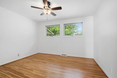an empty room with wooden floor cabinet and windows