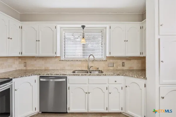 a kitchen with granite countertop white cabinets and white appliances