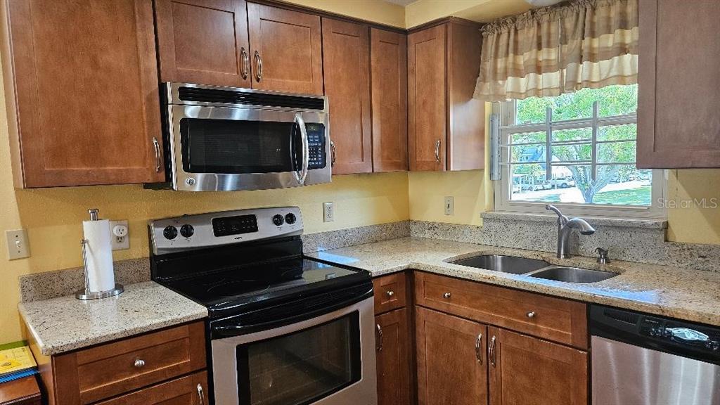 4600 98th Way North, Unit 210 St. Petersburg, FL 33708 - Photo 5 of 33 a kitchen with granite countertop a sink a stove and cabinets