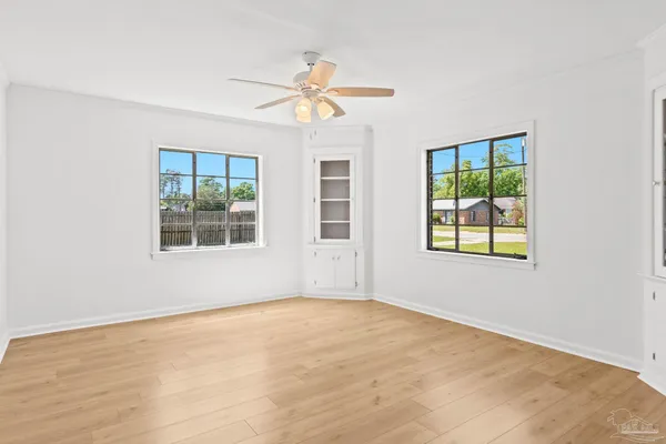 a view of an empty room with a ceiling fan and window
