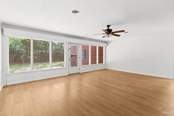 a view of an empty room with a window and wooden floor