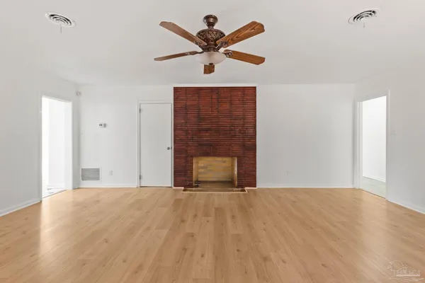 an empty room with a window and a chandelier fan