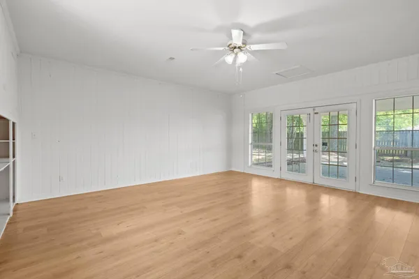 an empty room with wooden floor cabinet and windows