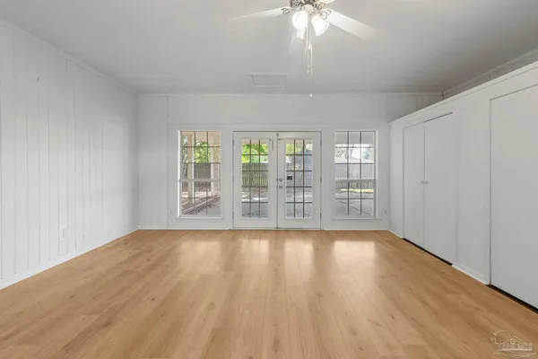an empty room with wooden floor a ceiling fan and windows